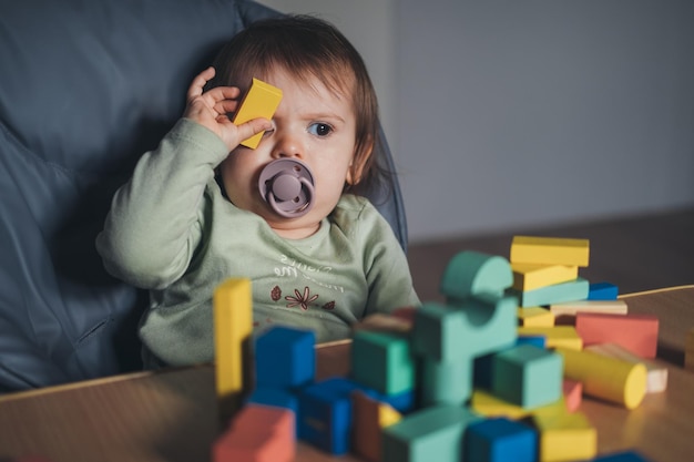 Bebê brincando com blocos de construção enquanto cobre o olho com uma das peças de desenvolvimento infantil