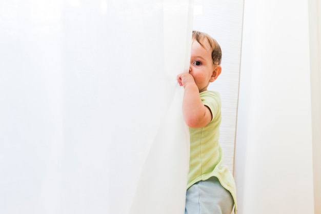 Bebê brincando com cortinas brancas