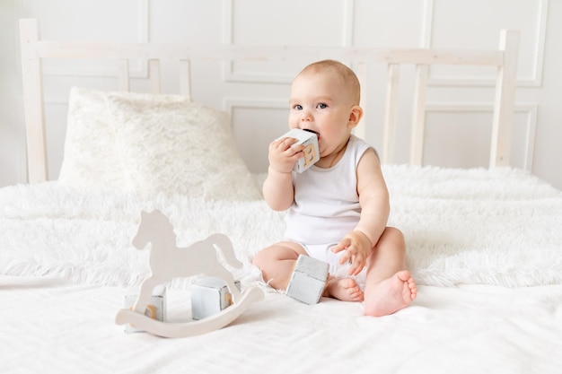 Bebê brincando com cubinhos de brinquedos de madeira na cama em um quarto bem iluminado