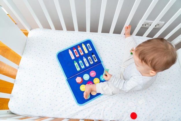 Foto bebê brincando com montessori ocupado livro sentado em um berço conceito de educação inicial