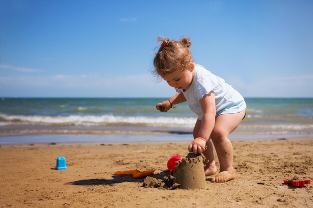 Bebê brincando na praia contra o céu azul