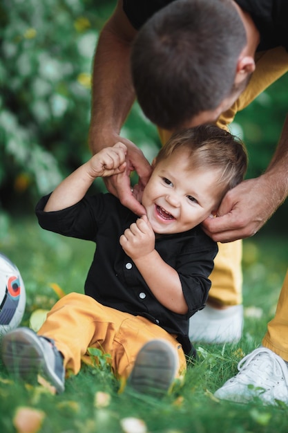 Bebê caucasiano branco brinca com o pai no gramado Bebê alegre brinca com o pai