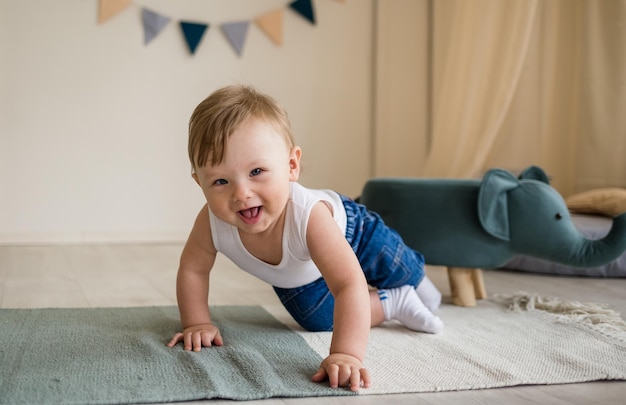 El bebé caucásico se arrastra por el suelo en la habitación de los niños con juguetes El bebé aprende a gatear