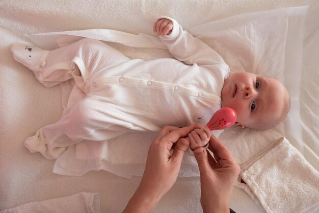 Bebé caucásico de dos meses en la cama acostado con un juguete de bolsa de frijoles