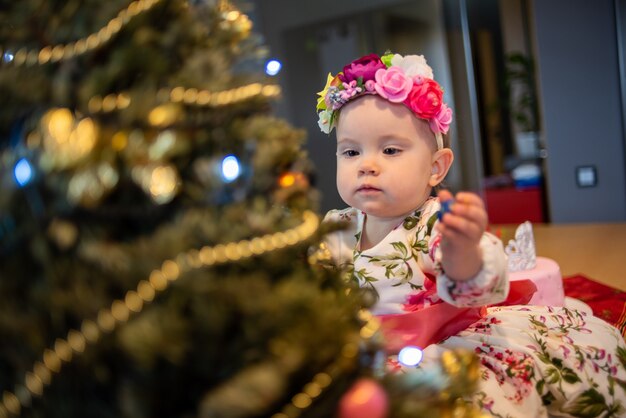 Bebé cerca del árbol de navidad antes de la fiesta de año nuevo