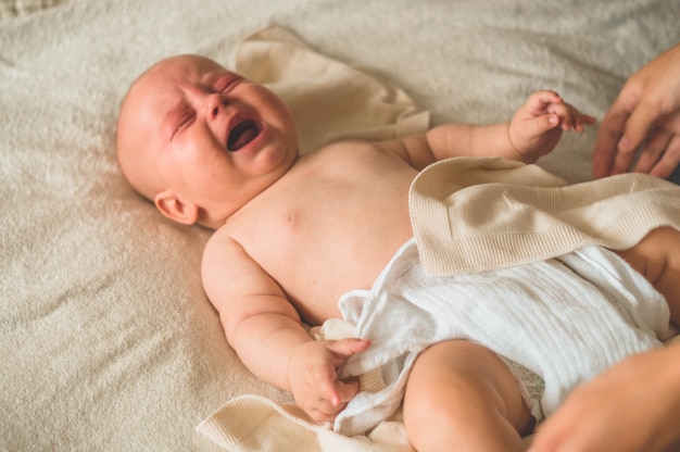 Bebê chorando deitado na cama