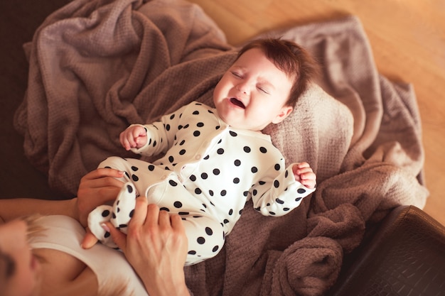 Bebê chorando nas mãos da mãe com dor de estômago