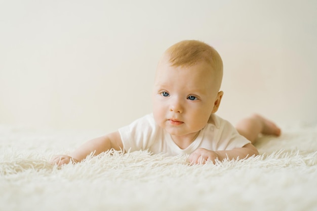 Un bebé de cinco meses está acostado boca abajo en la cama El concepto de cuidar a un bebé