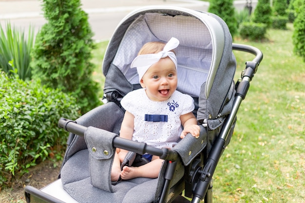 Bebé en un cochecito camina en verano con ropa blanca