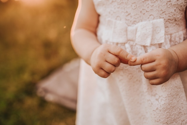 Bebê com as mãos da menina de vestido branco