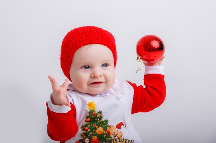 Foto bebê com fantasia de gnomo de natal segurando um globo de natal