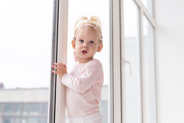 Bebê com implante coclear se divertindo em casa. surdez e conceito de tecnologia médica.