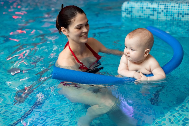 Bebê com mãe aprende a nadar na piscina