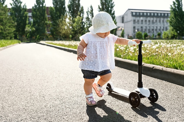 Bebê com scooter no parque aprendendo a andar