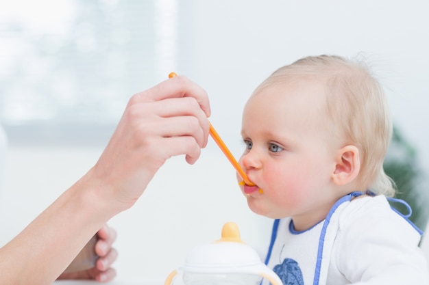 Bebê com uma colher de plástico na boca