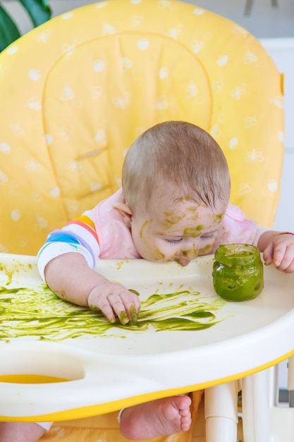 El bebé come puré de brócoli él mismo. Enfoque selectivo. Personas.