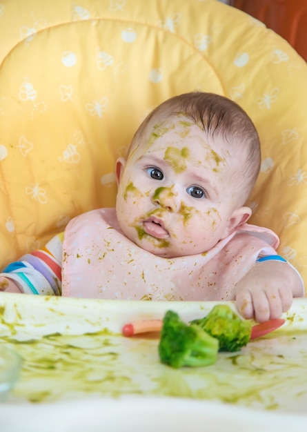 Foto el bebé come puré de brócoli él mismo. enfoque selectivo. personas.