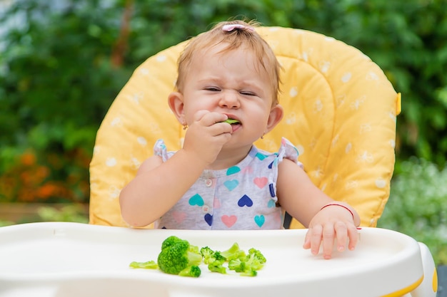 El bebé come trozos de verduras con brócoli. Enfoque selectivo. Niño.