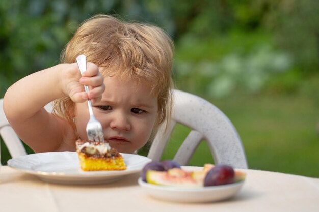 Foto bebê comendo bolo, criança comendo bolo na natureza em um piquenique, o conceito de uma doce infância feliz