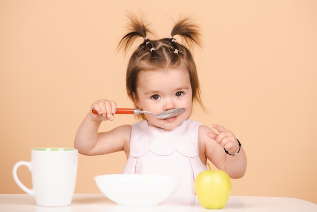 Bebê comendo comida de criança comendo comida saudável com uma colher no rosto de crianças engraçadas isoladas em estúdio