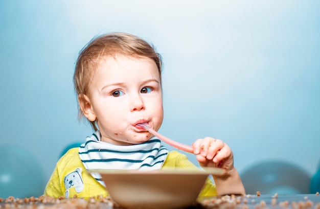 Bebé comiendo comida de niños niño divertido con plato y cuchara