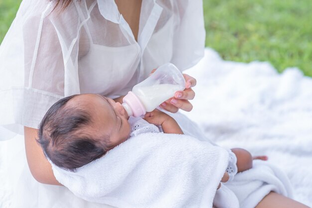 Bebê consome leite da mamadeira alimentada pela mãe