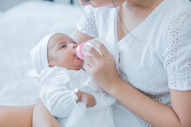 Bebê consome leite da mamadeira alimentada pela mãe