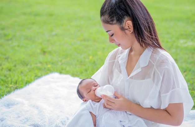 Bebé consume leche del biberón alimentado por la madre