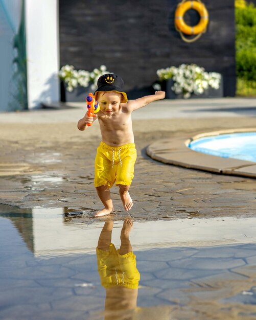 El bebé corre y juega en la zona de la piscina en verano