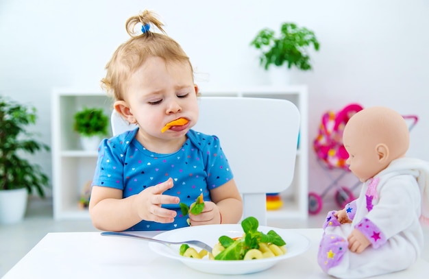 Bebê criança come macarrão com legumes Foco seletivo Comida