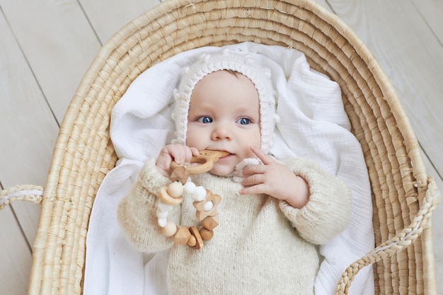 Bebé en cuna de mimbre con juguete de madera Día de la Madre Día de la Protección de los Niños Niño alegre infancia feliz