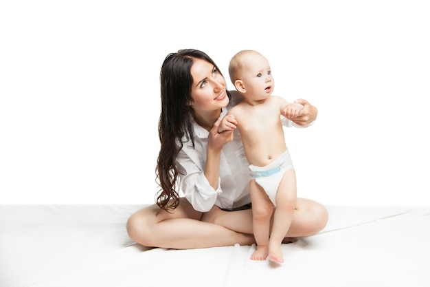 Bebê dando os primeiros passos com a ajuda da mãe em fundo branco