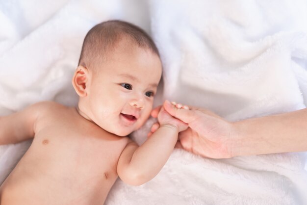 Bebê de retrato Ásia na cama branca