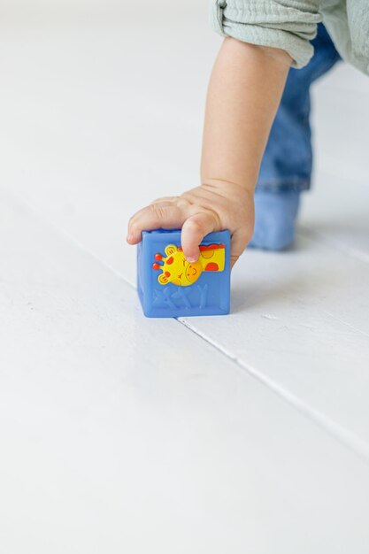 Bebê de um ano brinca com cubos no fundo branco do apartamento