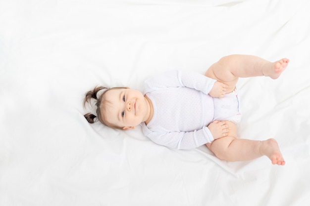 Bebê deitado na cama em casa em uma cama branca, o conceito de uma família feliz e amorosa com filhos