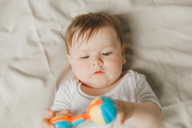 Un bebé con un dentador y un cascabel en una cama de algodón Teething Espacio de copia de artículos para niños