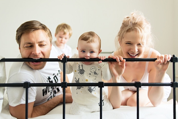 Bebé de dentición, familia joven para morder la cama, gracioso