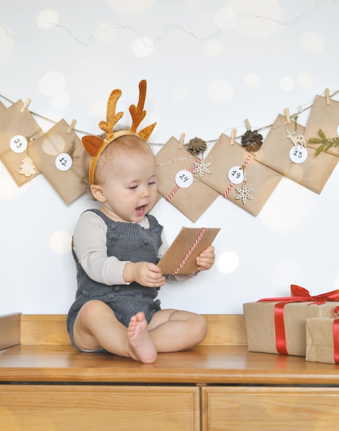 Bebé divertido desembala un regalo del calendario de Adviento Calendario de Adviento dispuesto en la pared