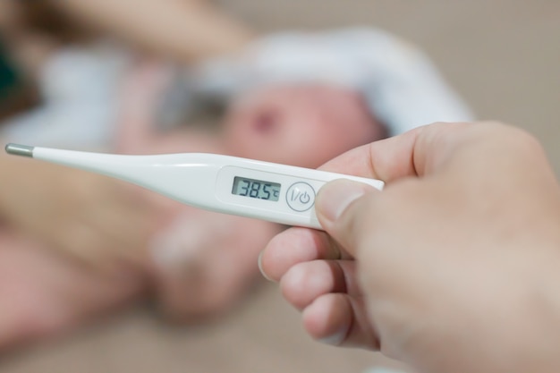 Bebê doença medicina febre da gripe e termômetro, mãe verificar a temperatura do bebê doente.