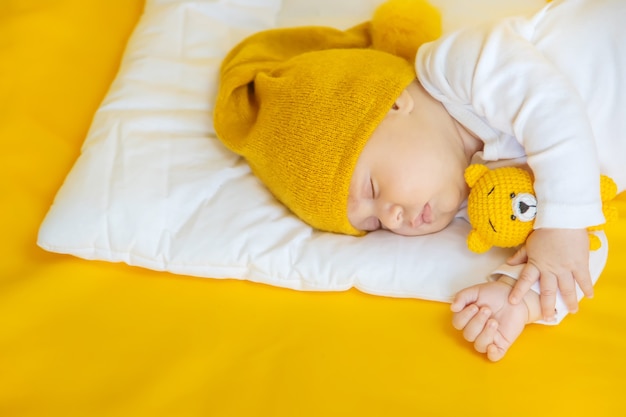 Bebê dorme com chapéu em um fundo amarelo, conceito de inverno e férias