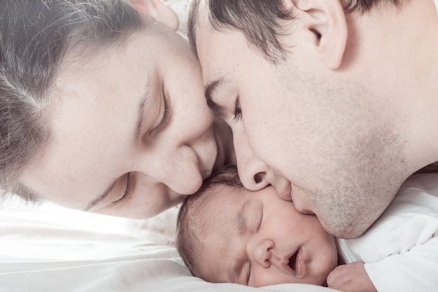 Bebê dormindo com mamãe e papai, rostos em close