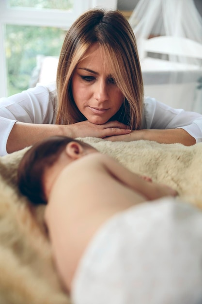 Bebê dormindo em um cobertor enquanto sua mãe olha