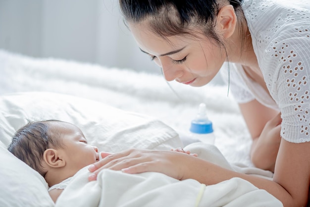 Bebé duerme madre asiática y toca a su hijo con ternura y cariño