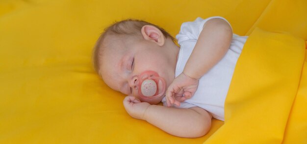 el bebé duerme en un niño de fondo amarillo