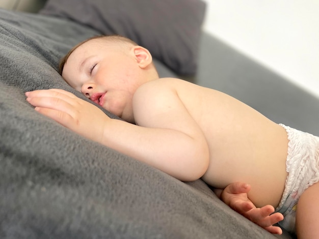 Foto un bebé duerme profundamente en su estómago durante el día en una manta gris