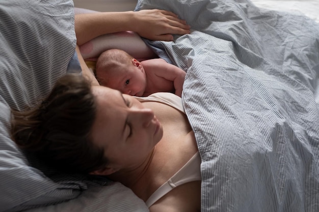 Bebé durmiendo junto a su madre en la cama.