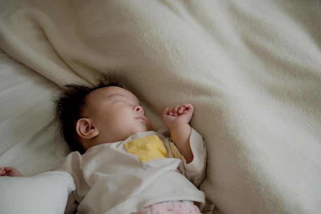 Un bebé durmiendo con una letra amarilla en la camisa.