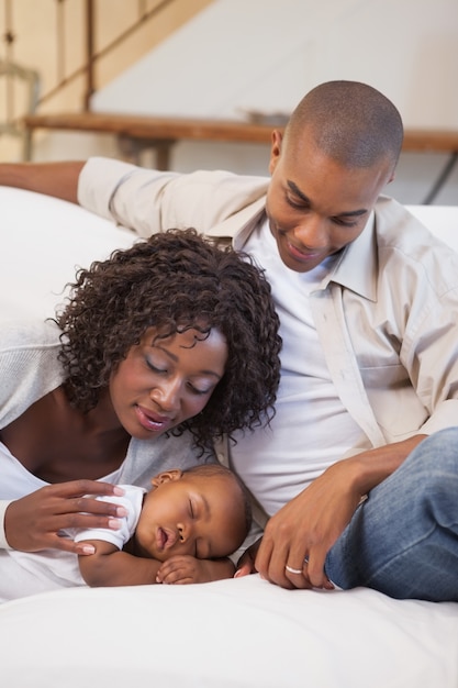 Bebé durmiendo pacíficamente en el sofá con padres felices