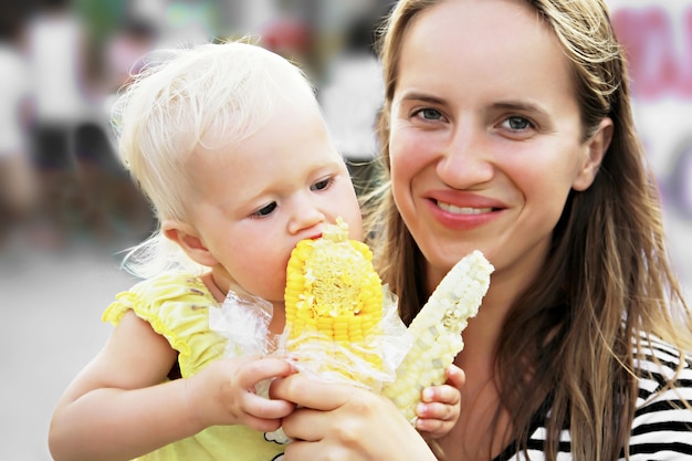 Bebê e mãe comendo milho