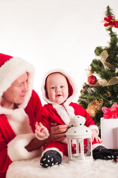 Bebê e mãe de natal sob o pinheiro isolado